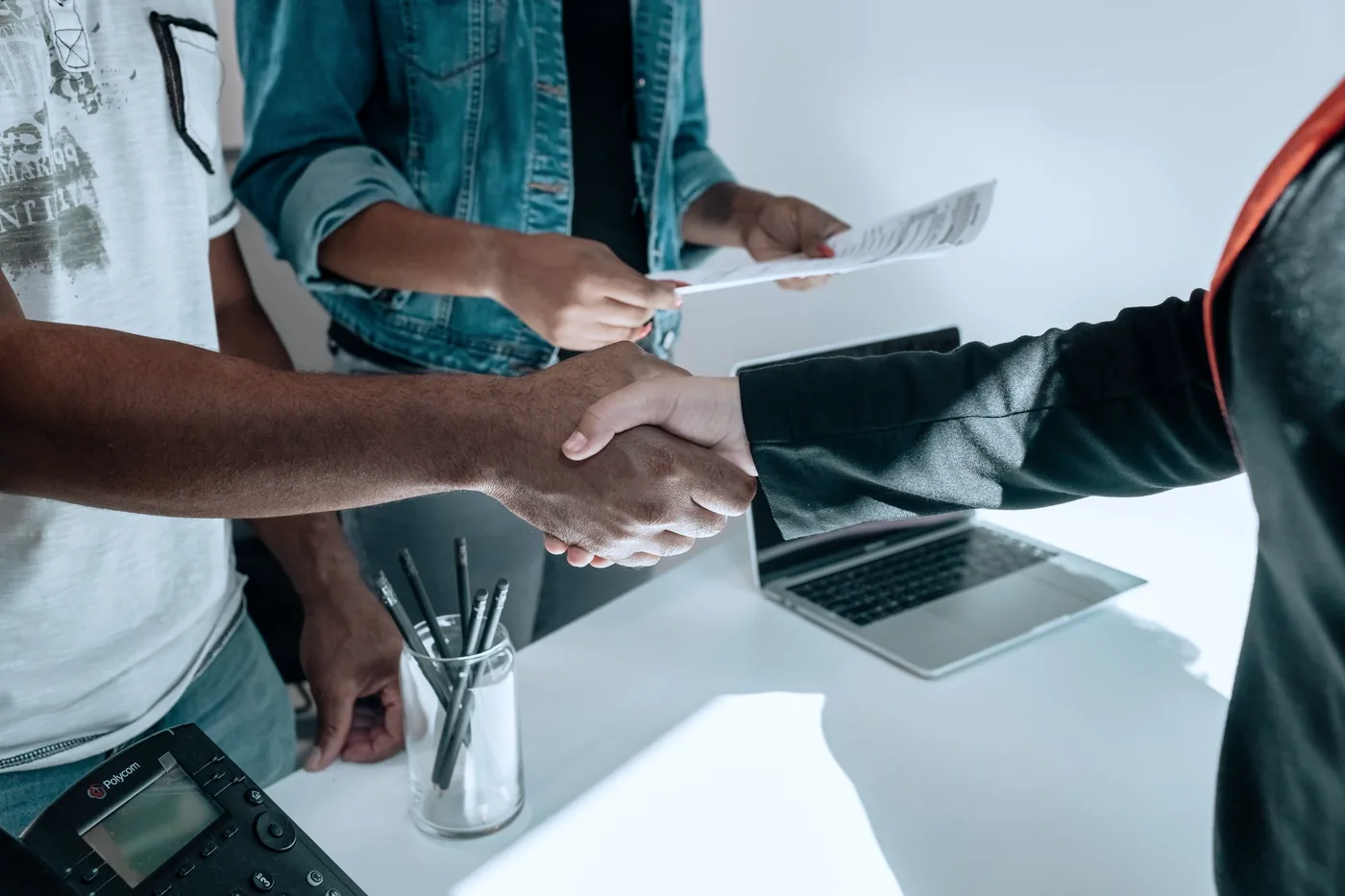 Een zakelijke handdruk boven documenten en een laptop