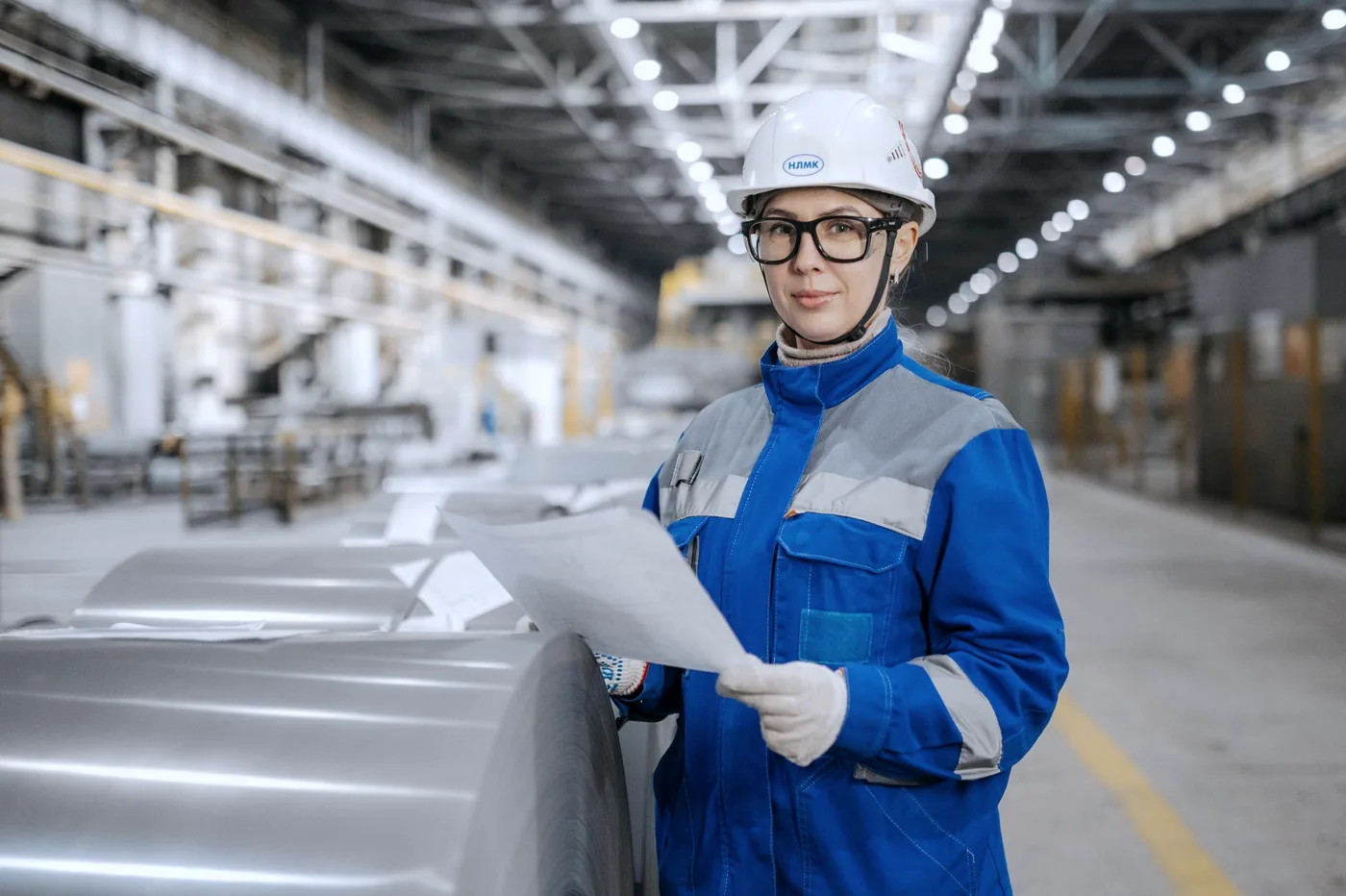 Een engineer in beschermende kleding inspecteert metaalvoorraad tijdens een kwaliteitscontrole